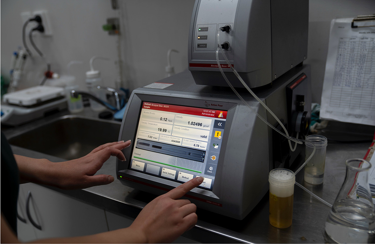 Brewery technician operating digital control panel.