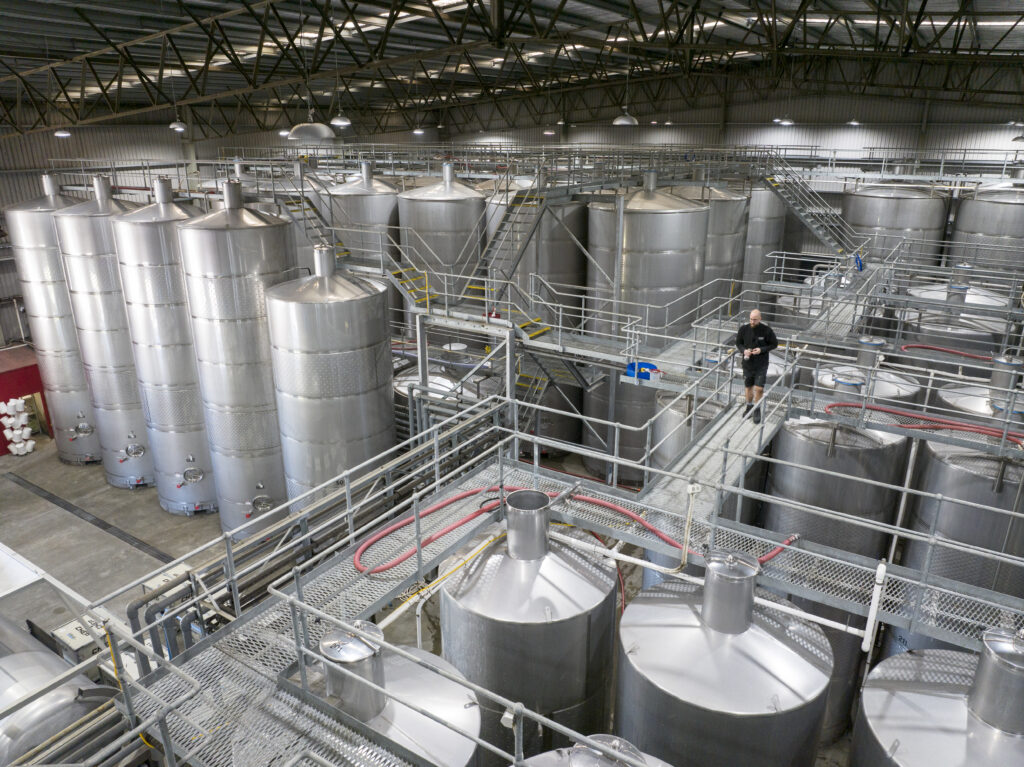 Row of stainless-steel fermentation tanks inside modern brewery.